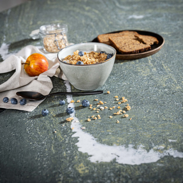 Aufnahme einer Granitarbeitsplatte auf der Brot, Gewürze und Gemüse liegt.