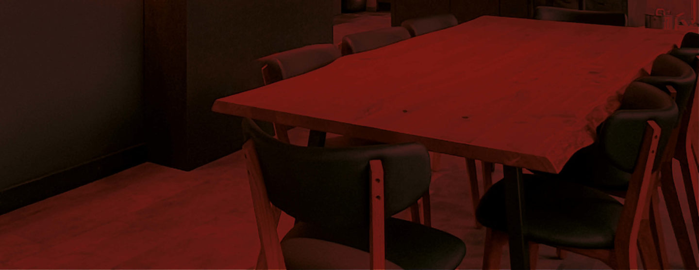 Großer Echtholz-Esstisch in der Ausstellung von Die Küchengalerie. Darüber liegt ein roter Farblayer