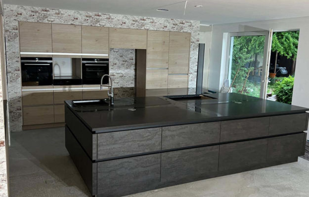 Schwarze-braune mit Hochschränken in Holzoptik und schwarzer Kochinsel.