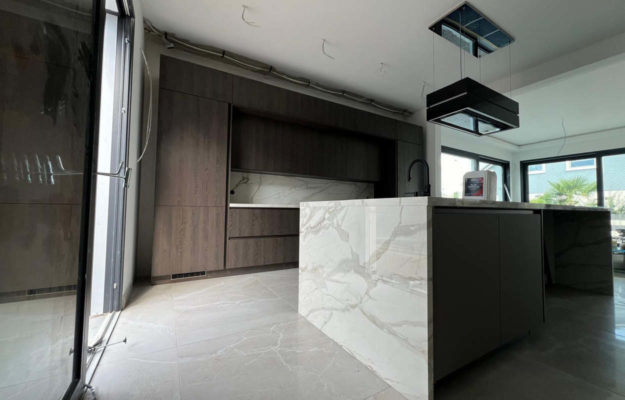 Dunkel Holzküche mit großer Kochinsel und weißer Natursteinarbeitsplatte.