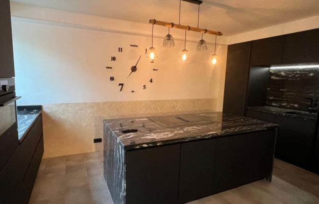 Schwarze Küche mit Kochinsel und Natursteinarbeitsplatte.