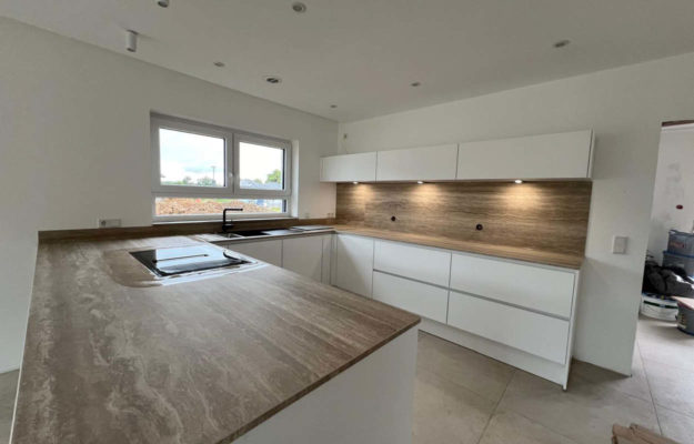 Weiße Küche mit braun-grauer Steinarbeitsplatte in U-Form.